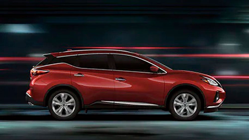 2023 Nissan Murano shown in profile driving down a street at night illustrating performance. | Fort Worth Nissan in Fort Worth TX