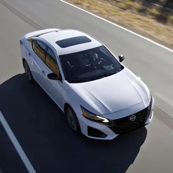 A gray altima driving on the road.