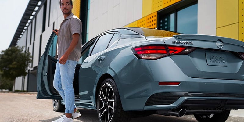 A man getting of of a blue car.