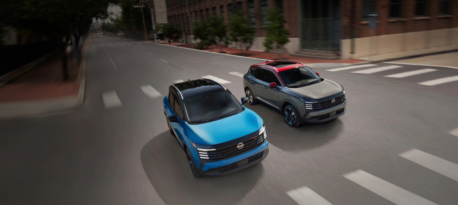 2 small suvs driving on a paved road in the city