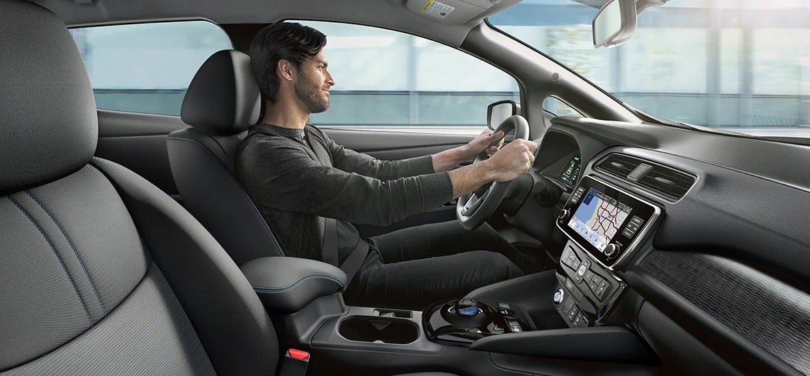 A driver seated in the 2025 Nissan Leaf, with a focus on the interior comforts and advanced driving features.
