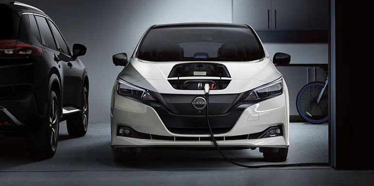 The 2025 Nissan Leaf plugged into a charging station, highlighting its electric performance capabilities and zero emissions.