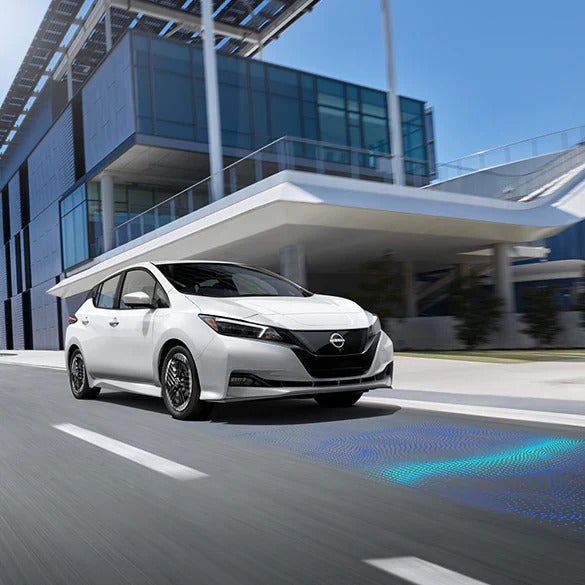The 2025 Nissan Leaf driving on a highway, showcasing safety features like lane assist and intelligent driving aids.