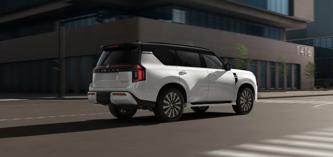 a white nissan armada parked next to a building