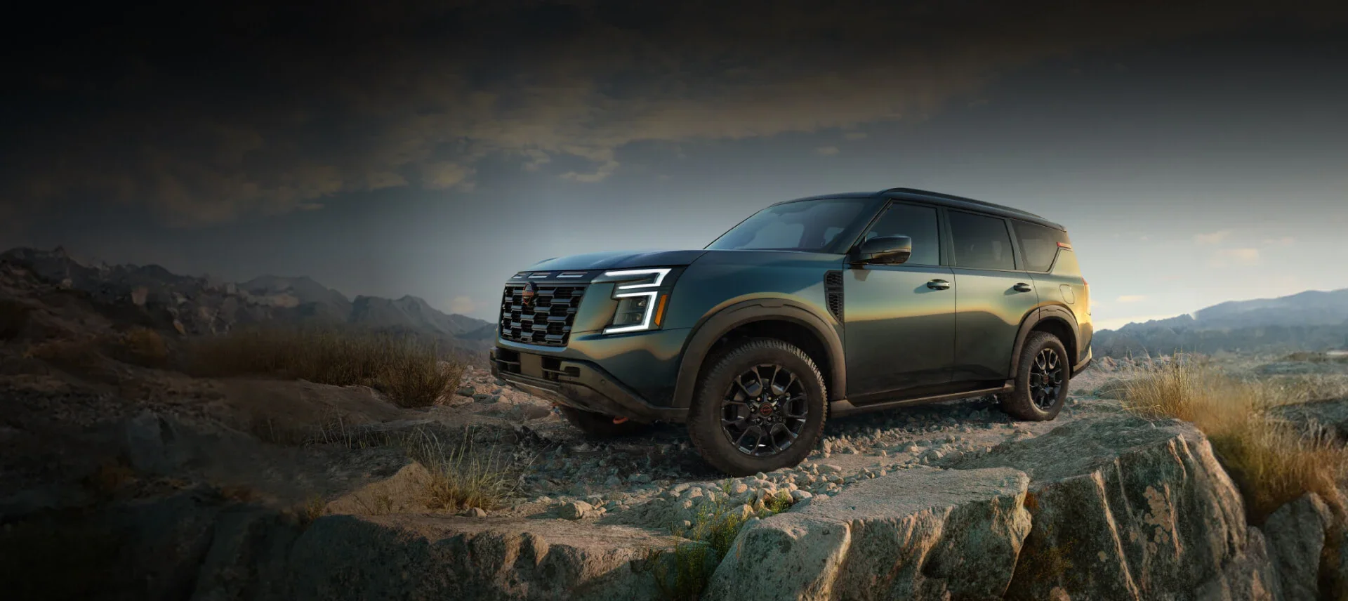 a green nissan armada parked on a cliff at sunset