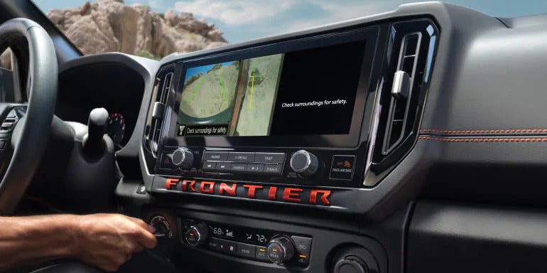 Close-up of the 2025 Nissan Frontier's 12.3-inch touchscreen displaying a split-screen view with navigation and surround-view camera features.