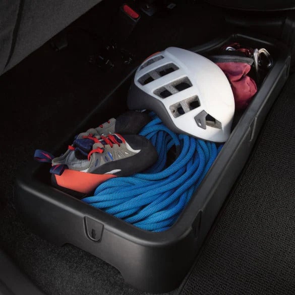 Under-seat storage compartment in the 2025 Nissan Frontier with climbing gear, including a helmet, shoes, and a rope, demonstrating its smart storage solutions.