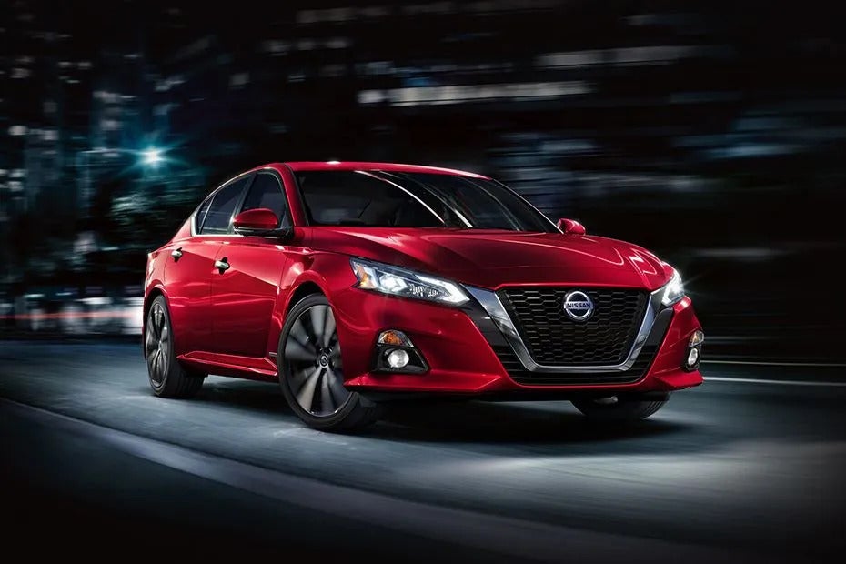 A red nissan altima driving on the road.
