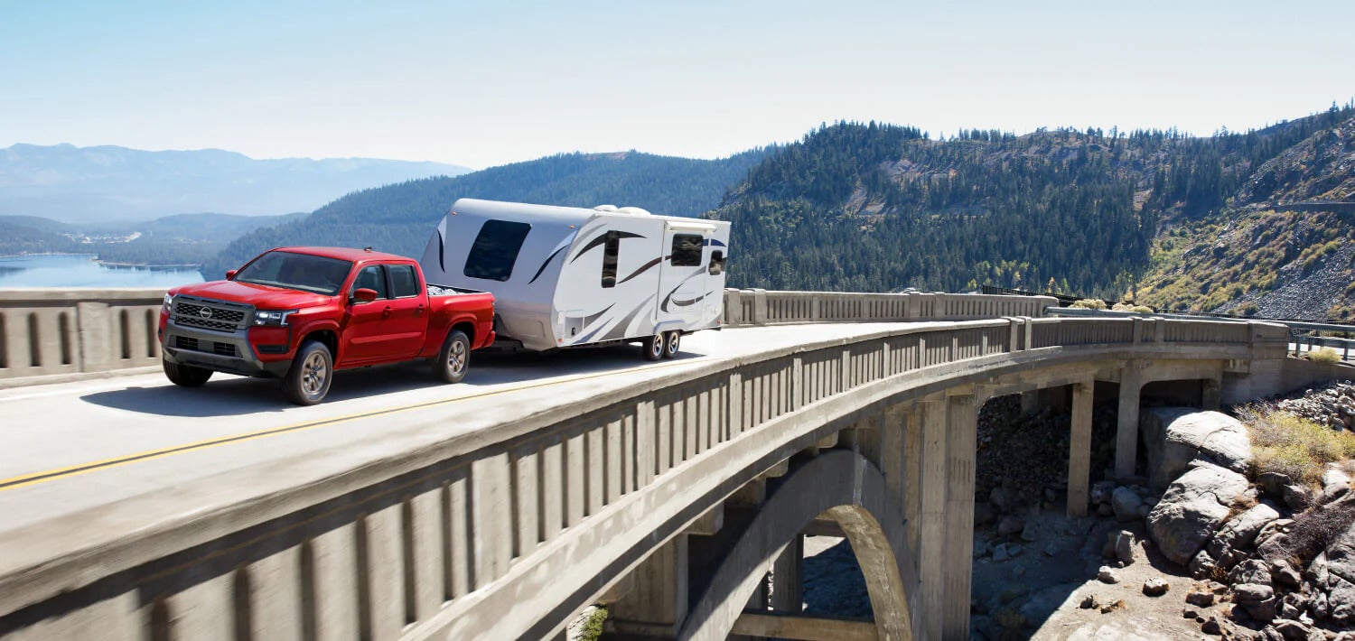 A red truck pulling a trailer on the road.
