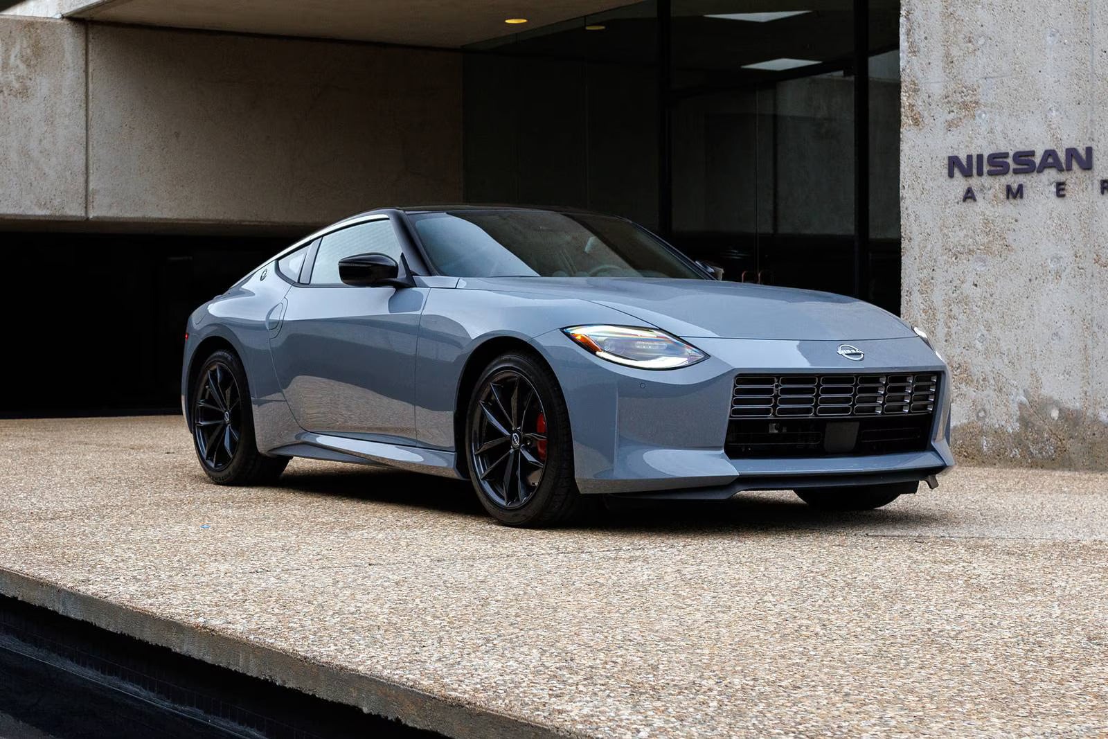 A gray car sitting parked in front of a building.