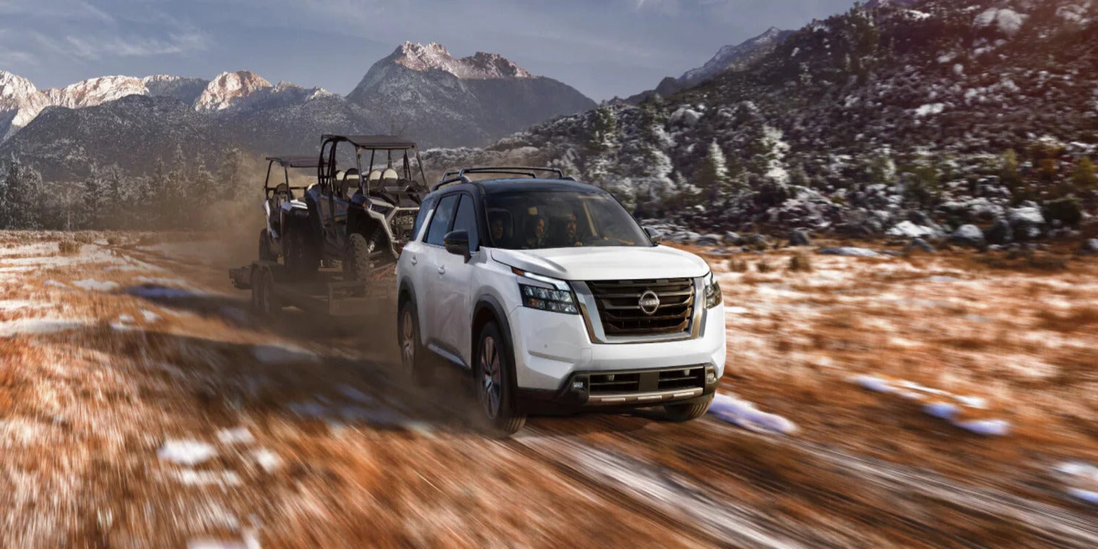 A white pathfinder pulling a trailer.