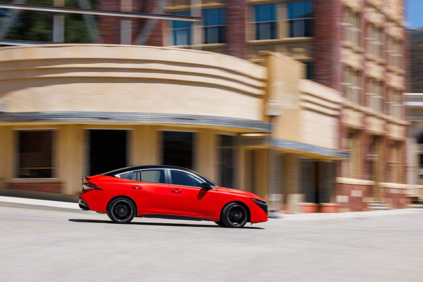 A red sentra driving on the road.