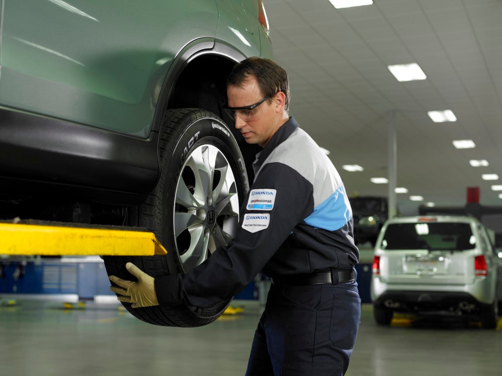 A man looking at the tires on a car.