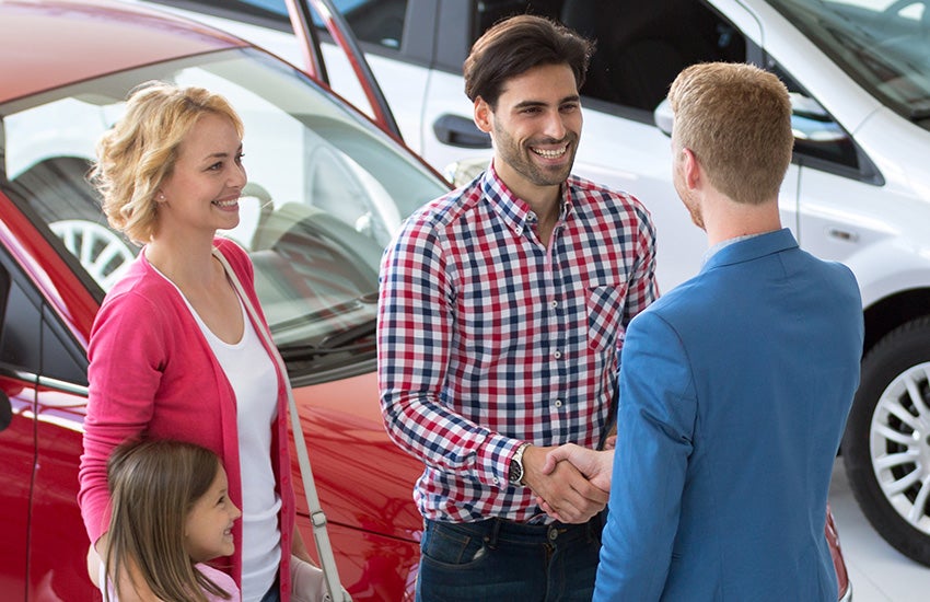 A family smiling while the dad shakes a hand.